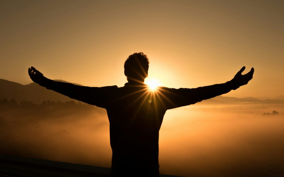 silhouette photo of man on cliff during sunset